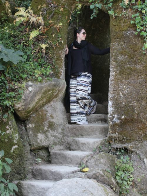 Gina Bley walking down the stairs of an old temple wearing a black top and some stripy pants