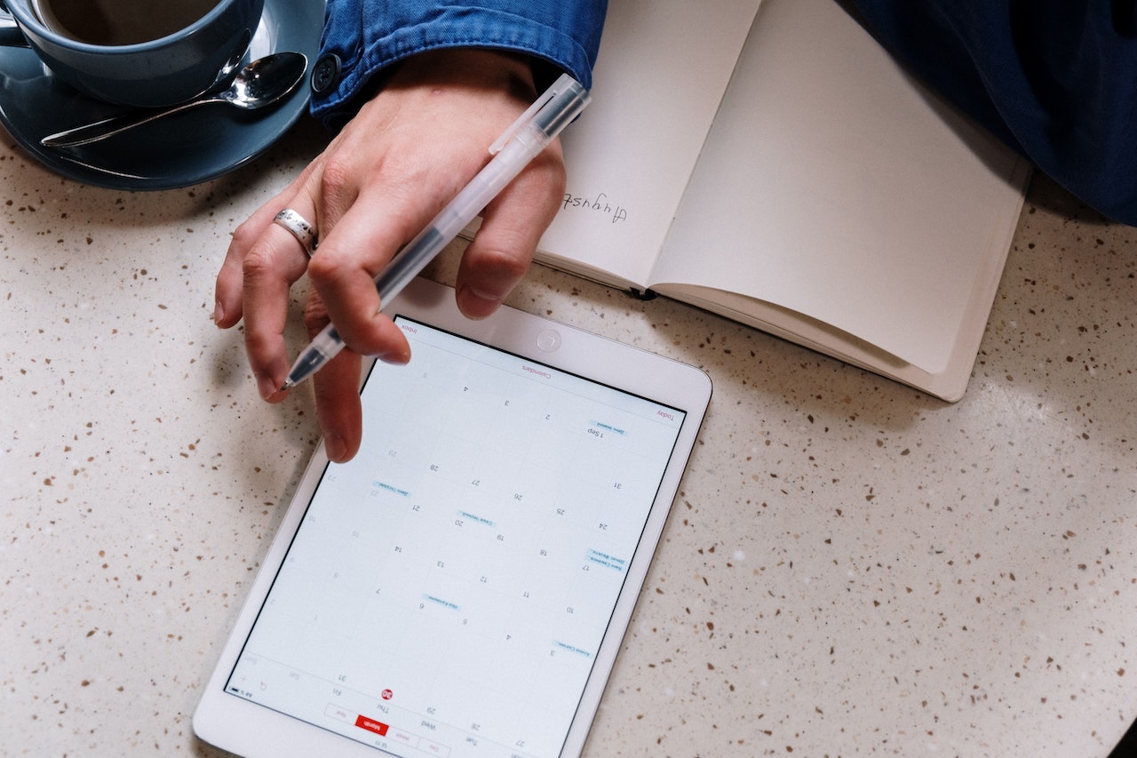 Image for the article "Daily Routines of Successful People" shows a notebook and tablet on a table with a hand holding a pencil from a birds-perspective