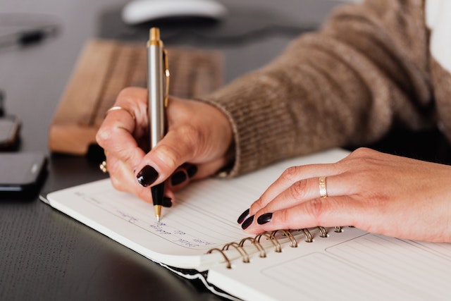 Image for the article "The Power of Journaling for Personal Insight" shows a woman sitting at a table with a journal writing down her thoughts