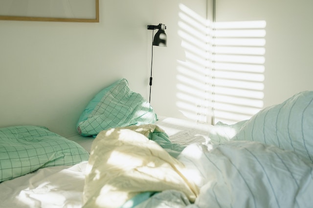 Image for the article "Why Sleep is the Foundation of Change" shows an unmade bed with light and shadow play on the wall