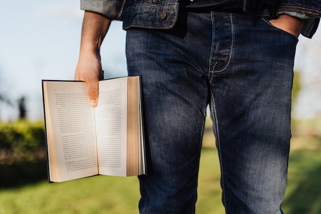 Image for the article "Dealing with Change" shows a man holding an open book dressed in all denim