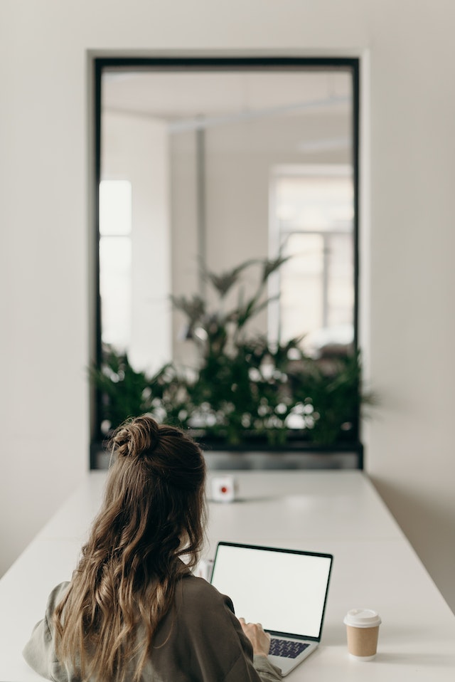 Image for the article "Dealing with Change" shows a woman working at a table in front of a mirror with a laptop in front of her