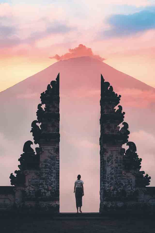 Image for the article "Steps to Cultivate a Growth Mindset" shows a tiny human standing in a temple in Bali during the sunrise with a gigantic mountain in the far back